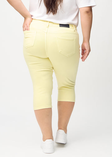 Lysegule skinny capris set bagfra på en plus-size model, så man kan se hele produktet.