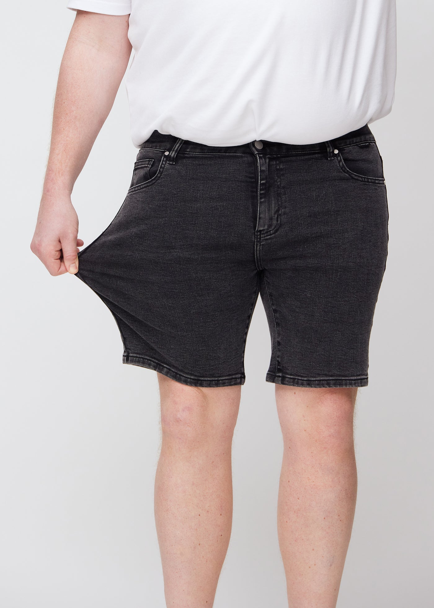 Plus-size model strækker shortsene ved låret for at vise stretch.