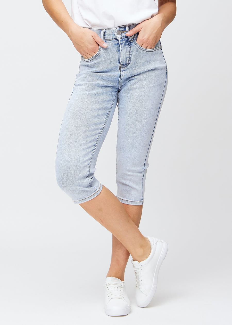 Lyseblå denim slim capris, farve Waves, med tætsiddende pasform der former benene og slutter lige under knæet – set forfra.