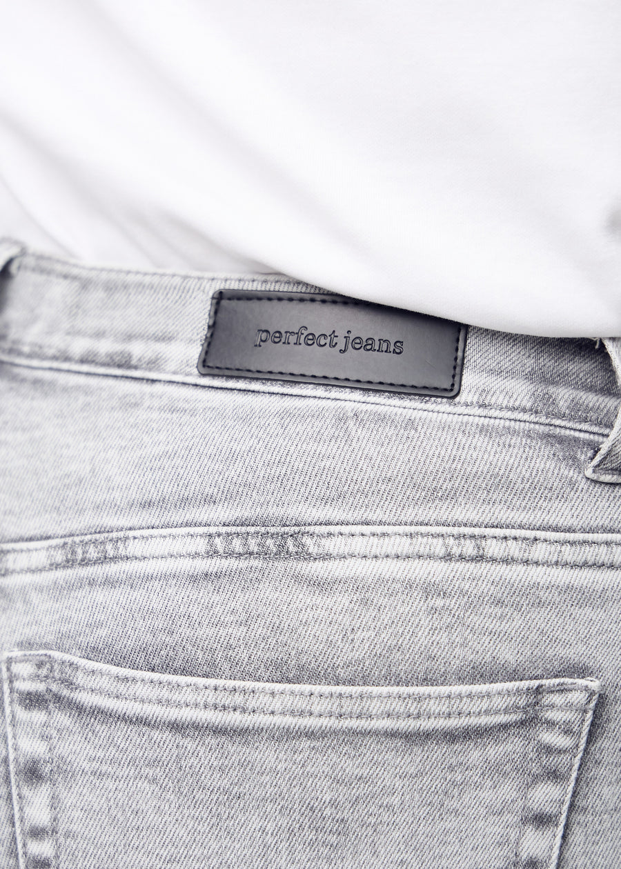 Baglommen på lysegrå denim set tæt på – tydeligt logo og tekstur vist på en plus-size model.