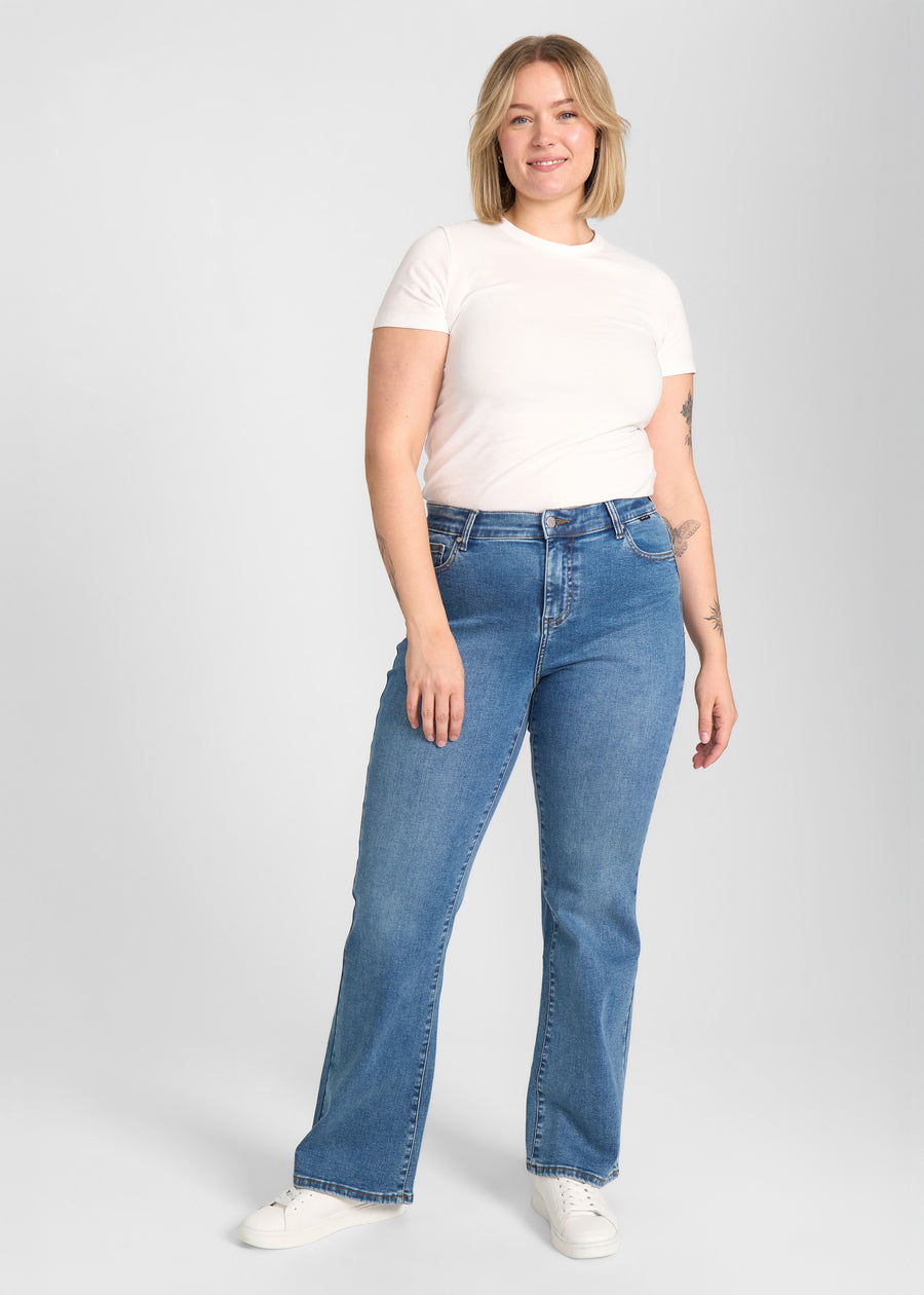 Fuldt billede af model i blå denim bootcut jeans på en plus-size model.