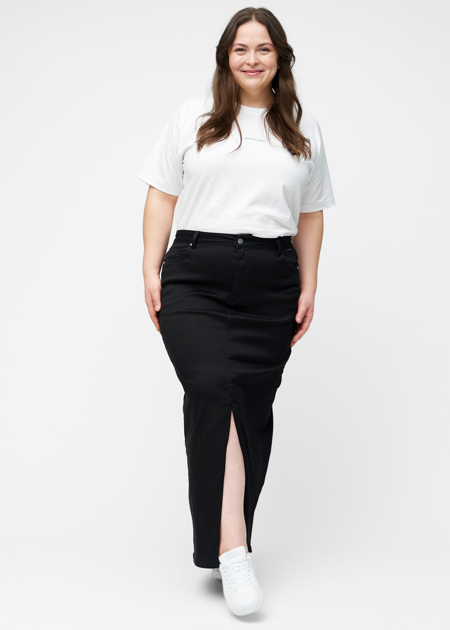 Plus-size model viser lang, sort jeansnederdel i farven Ravens med regulær pasform i bevægelse og demonstrerer slids og materiale.