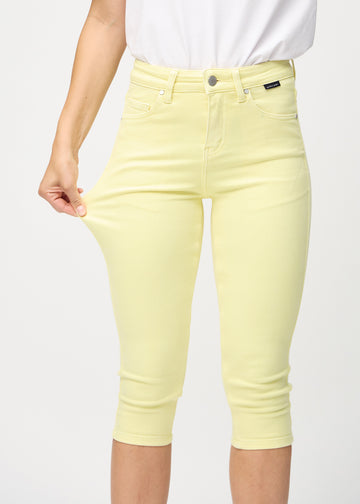 Kvinde der strækker i et par lysegule capris