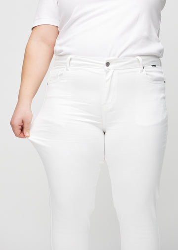 Plus-size model strækker jeansene ved låret for at vise stretch.