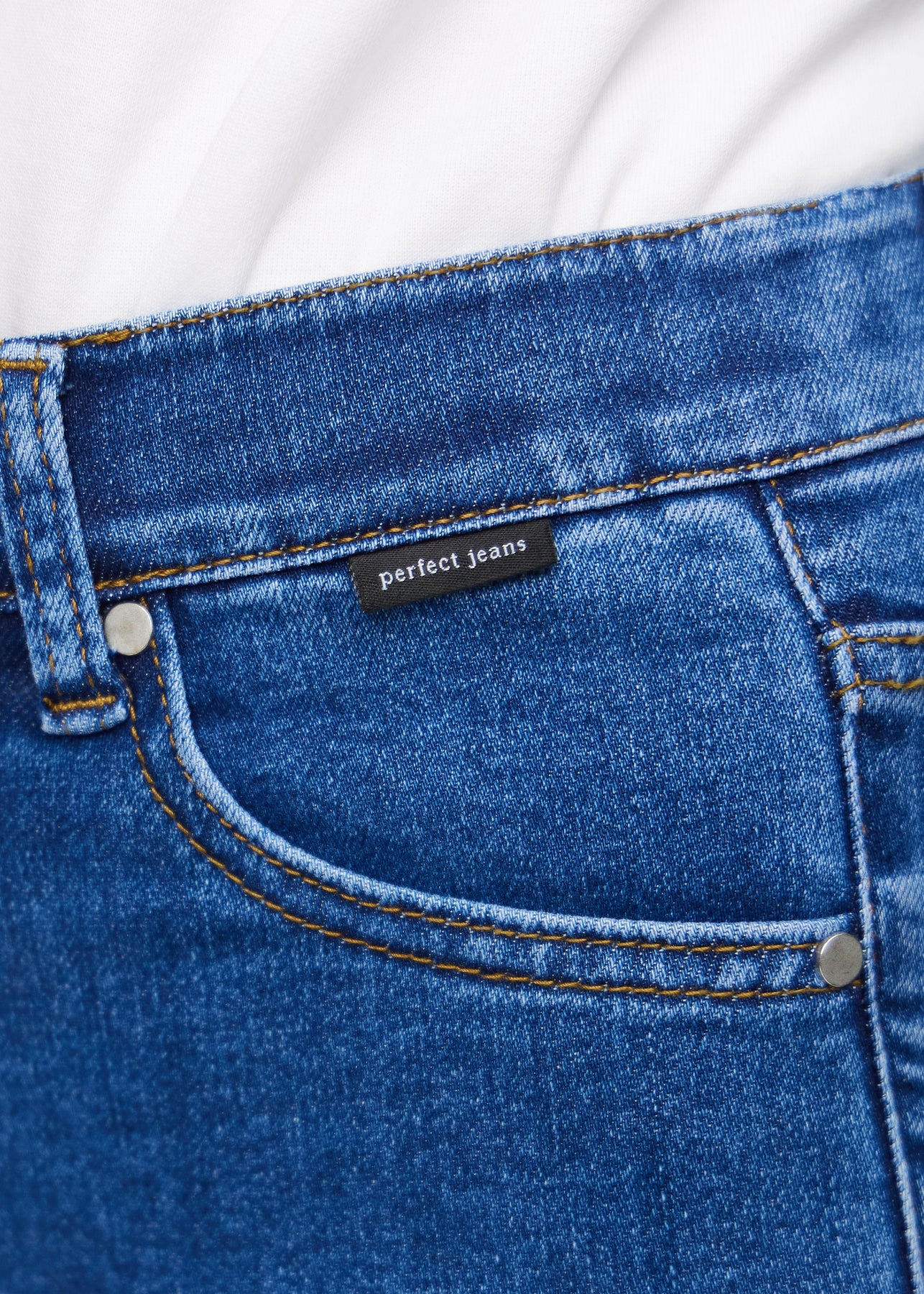 Nahaufnahme von dunkelblauem Denim mit Perfect Jeans Logoetikett an der Vorderkante der Tasche.