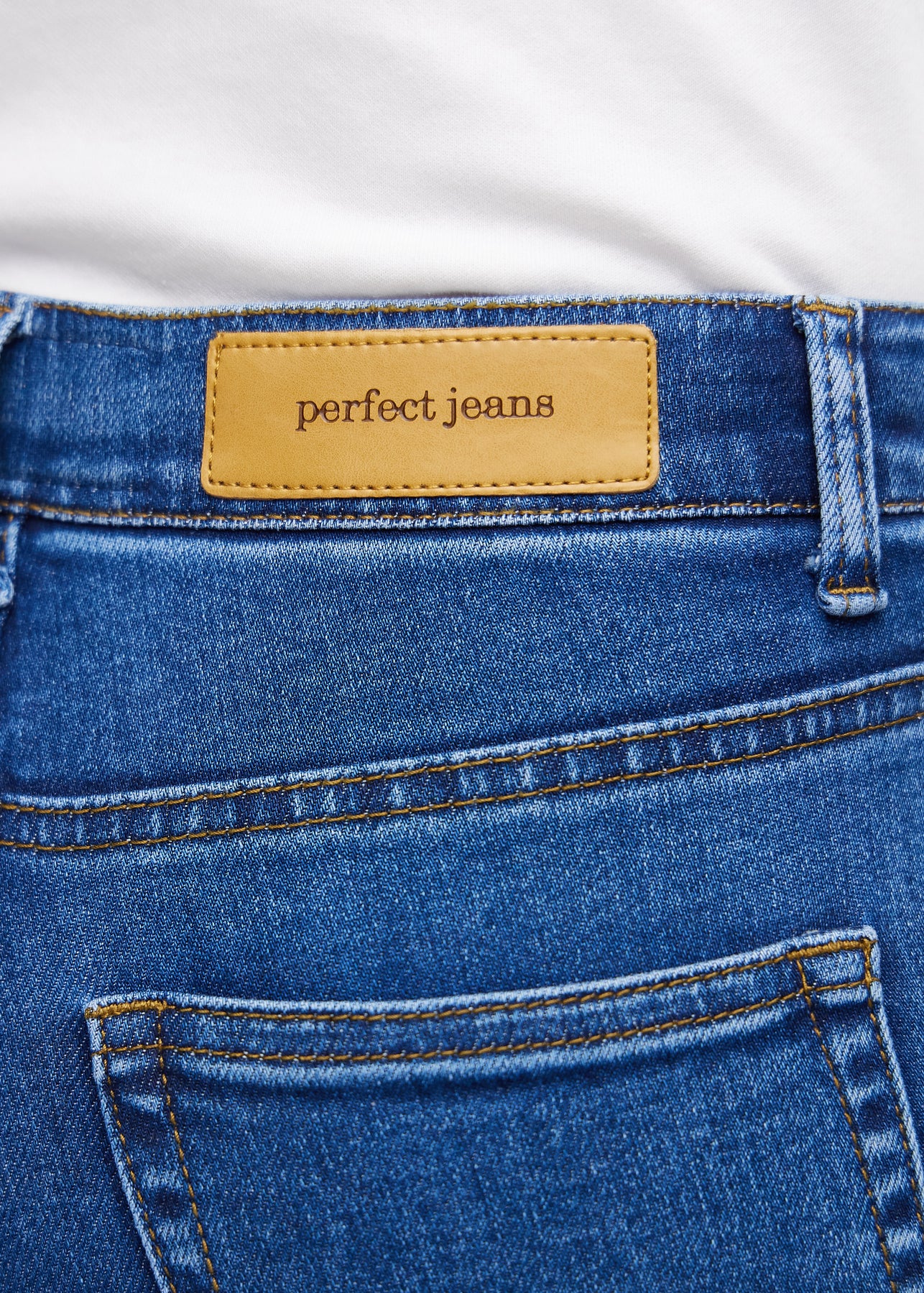 Nahaufnahme von dunkelblauem Denim mit Perfect Jeans Lederpatch hinten am Bund.