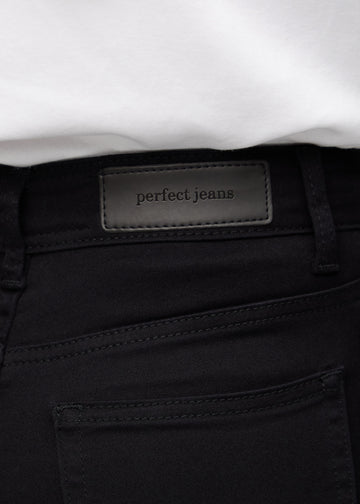 Nærbillede af sort jeansmateriale med Perfect Jeans læderpatch bagpå i taljen.