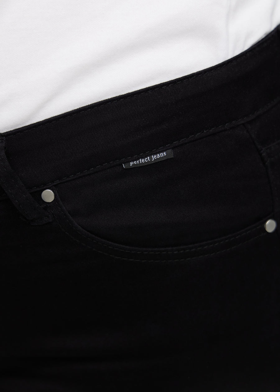 Nærbillede af sort jeansmateriale med Perfect Jeans logoetiket ved forlommekanten, på en plus-size model.