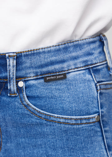 Nahaufnahme von blauem Denim mit Perfect Jeans Logoetikett an der Vorderkante der Tasche.