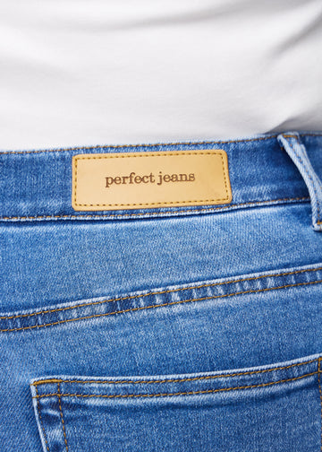 Nahaufnahme von blauem Denim mit Perfect Jeans Lederpatch hinten am Bund auf einem Plus-Size-Modell.