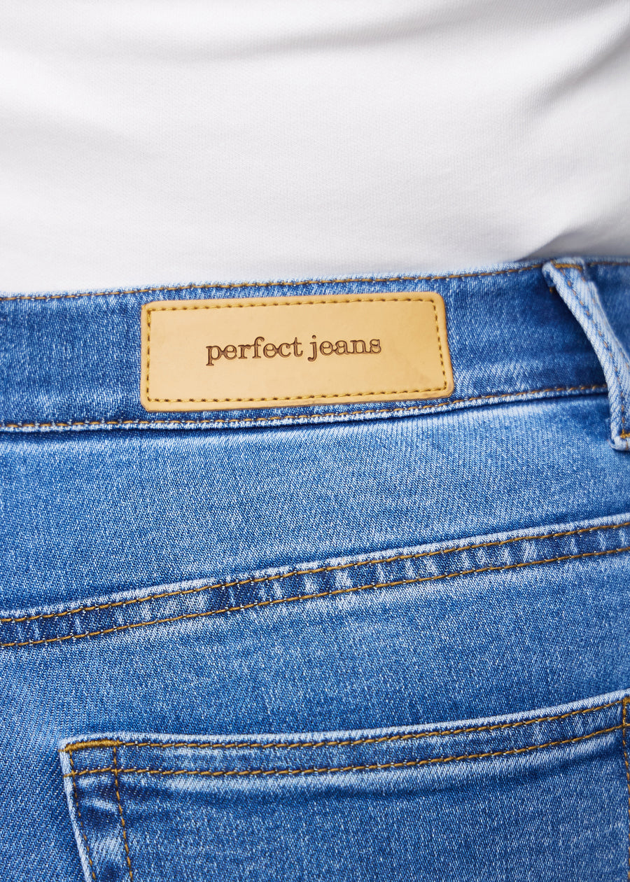 Nahaufnahme von blauem Denim mit Perfect Jeans Lederpatch hinten am Bund auf einem Plus-Size-Modell.