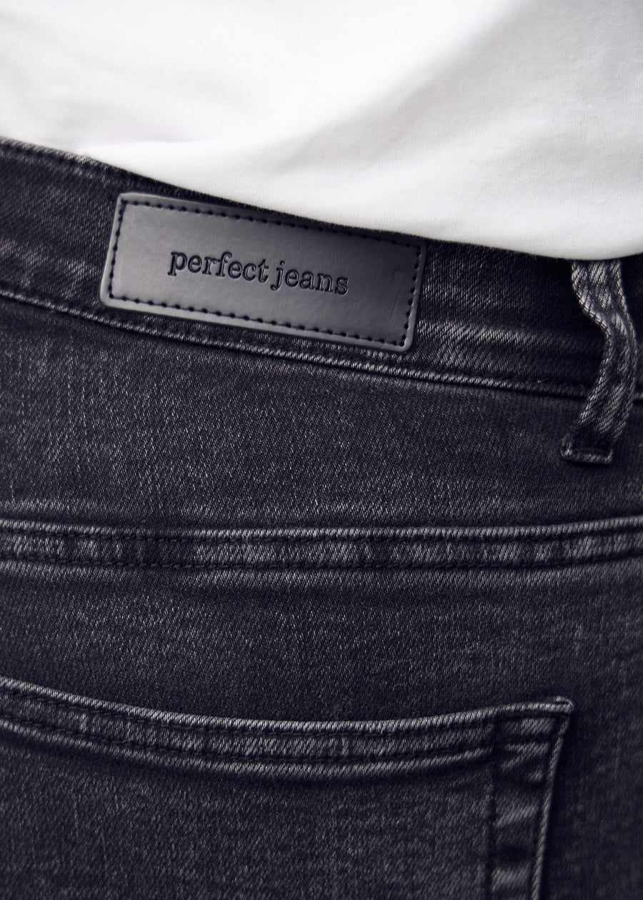Nærbillede af mørkegrå denim med Perfect Jeans læderpatch bagpå i taljen.