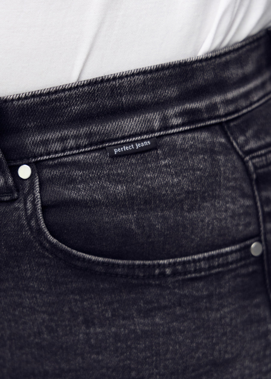 Nærbillede af mørkegrå denim med Perfect Jeans logoetiket ved forlommekanten, på en plus-size model.