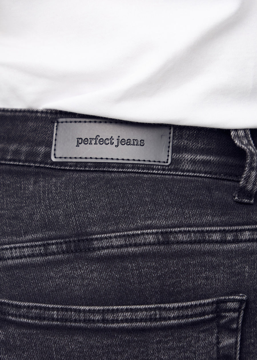 Nærbillede af mørkegrå denim med Perfect Jeans læderpatch bagpå i taljen, på en plus-size model.