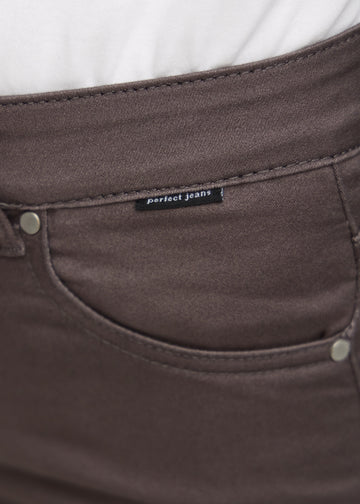 Nærbillede af gråbrunt jeansmateriale med Perfect Jeans logoetiket ved forlommekanten.