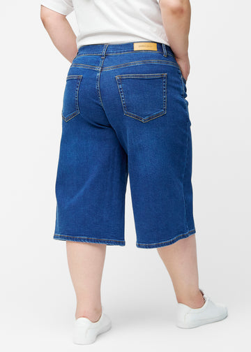 Løse, mørkeblå denim capris i farven Oceans set bagfra på plus-size model, så pasform og længde kan ses.