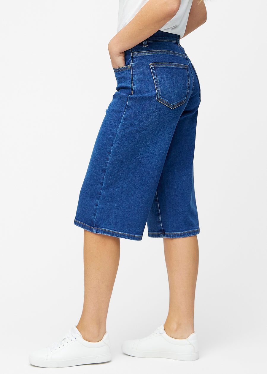 Løse, mørkeblå denim capris i farven Oceans set fra siden på model, hvor den brede pasform og længden til lige under knæet er synlig.