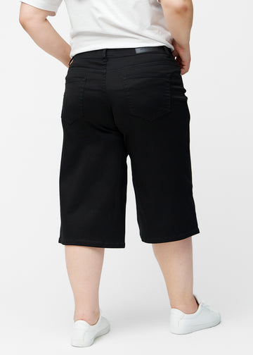Løse, sorte capris i farven Ravens set bagfra på plus-size model, så pasform og længde kan ses.