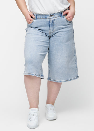 Lockere, hellblaue Denim-Capris in der Farbe Waves von vorne am Plus-Size-Model, die an der Hüfte sitzen und locker fallen.