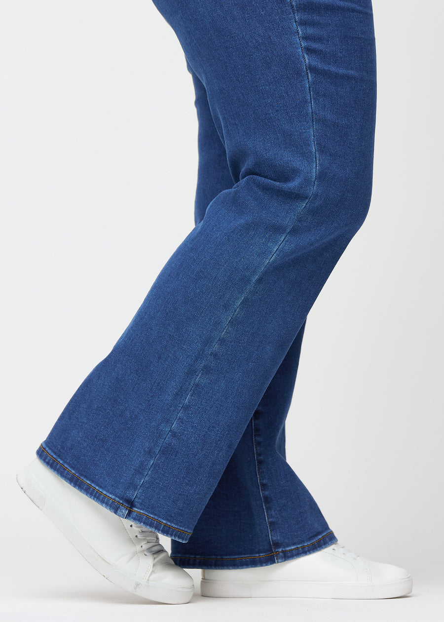 Dunkelblaue Mid-Rise-Bootcut-Jeans in der Farbe Oceans. Nahaufnahme am Knöchel eines Plus-Size-Model, um den leichten Schlag am Beinabschluss zu zeigen.