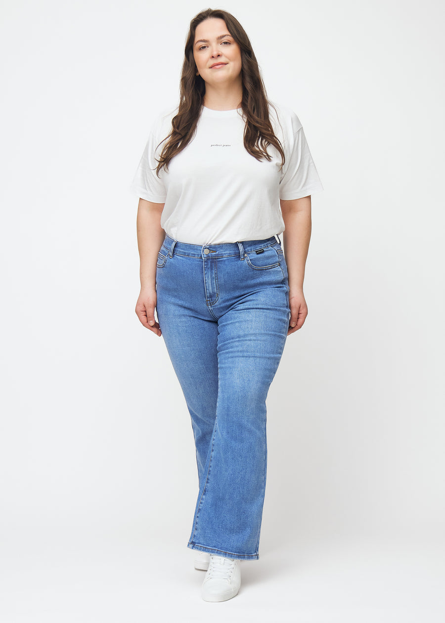 Blaue Mid-Rise-Bootcut-Jeans in der Farbe Rivers. Ganzkörperansicht eines Plus-Size-Model in den Jeans.