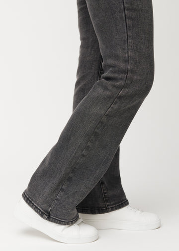 Dunkelgraue Mid-Rise-Bootcut-Jeans in der Farbe Shadows. Nahaufnahme am Knöchel eines Model, um den leichten Schlag am Beinabschluss zu zeigen.
