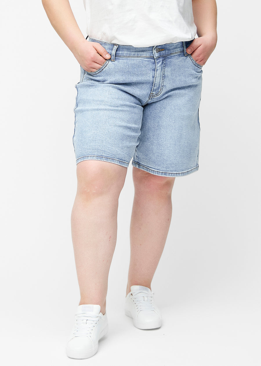 Lockere, hellblaue Denim-Shorts in der Farbe Waves von vorne am Plus-Size-Model, die an der Hüfte sitzen und locker fallen.