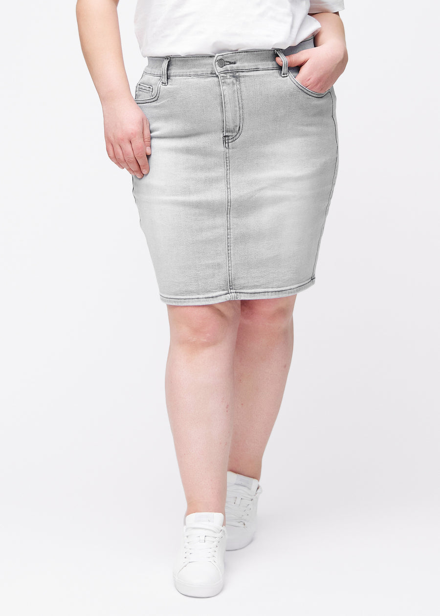 Lysegrå, tætsiddende og knælang denimnederdel set forfra på plus-size model.
