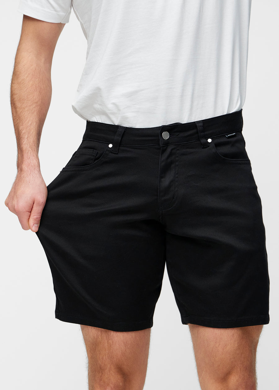 Modell dehnt schwarze Shorts für Herren in der Farbe Ravens am Oberschenkel, um den Stretch des Materials zu zeigen.