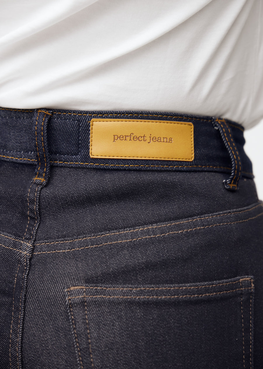 Nahaufnahme von dunkelblauem denim mit perfect jeans lederpatch bagpå i taljen.