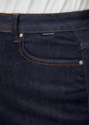 Nahaufnahme von dunkelblauem denim med perfect jeans logoetikett ved forlommekanten på plus-size-model.