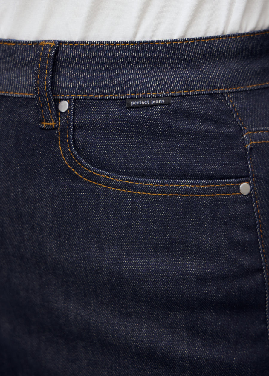 Nahaufnahme von dunkelblauem denim med perfect jeans logoetikett ved forlommekanten på plus-size-model.