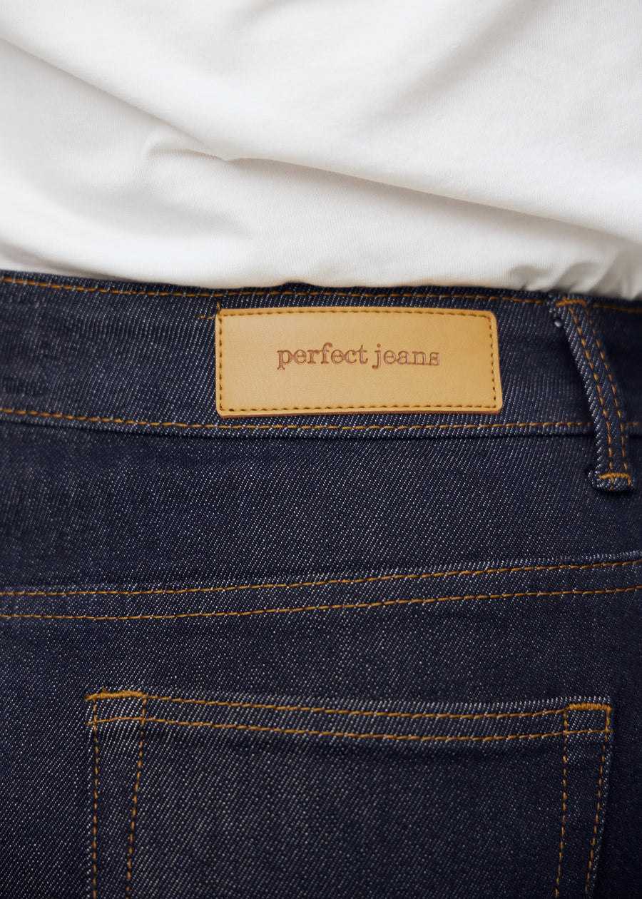 Nahaufnahme von dunkelblauem denim med perfect jeans lederpatch bagpå i taljen på plus-size-model.
