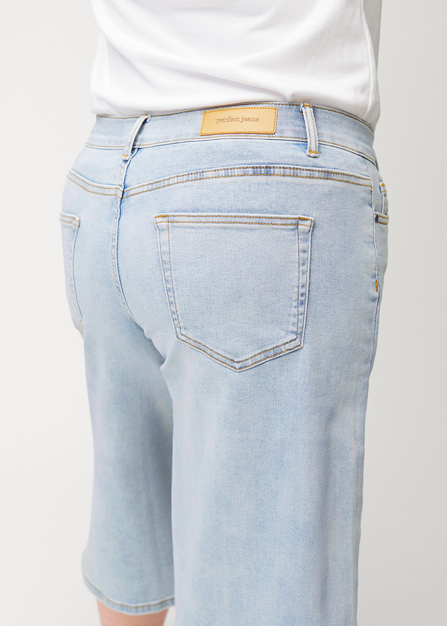 Nahaufnahme von hinten: lockere, hellblaue Waves Denim-Capris an einem Plus-Size-Model, die Passform und Details zeigen.