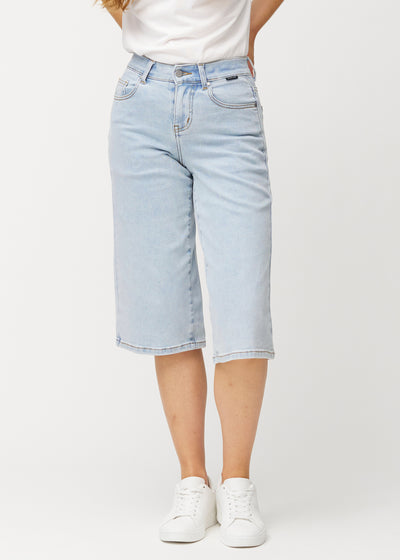 Løse, lyseblå denim capris i farven Waves, der sidder til ved hoften og falder løst ned over lårene til lige under knæet, set forfra.
