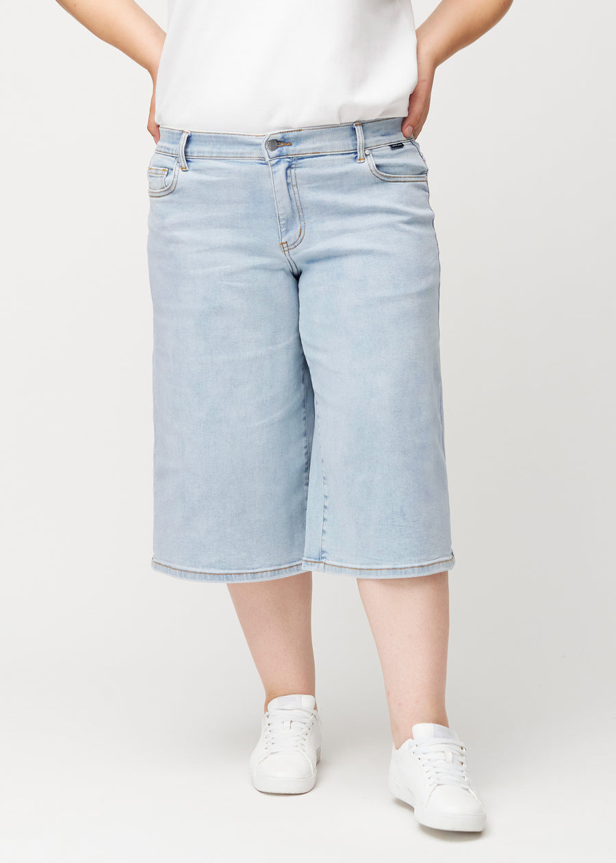 Plus-Size-Model in lockeren, hellblauen Waves Denim-Capris von vorne, die an der Hüfte anliegen und locker fallen.