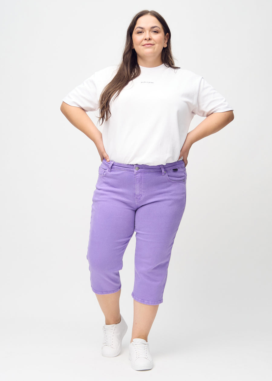 Ganzkörperbild eines Plus-Size-Models in lila regular Capris.