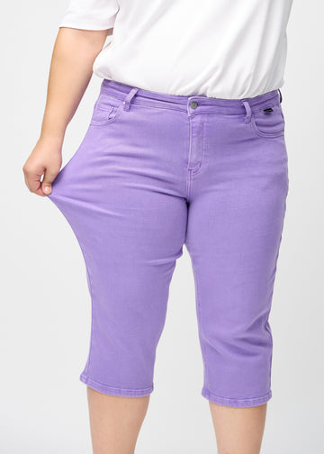 Das Plus-Size-Model zieht die Capris am Oberschenkel auseinander, um den Stretch zu zeigen.