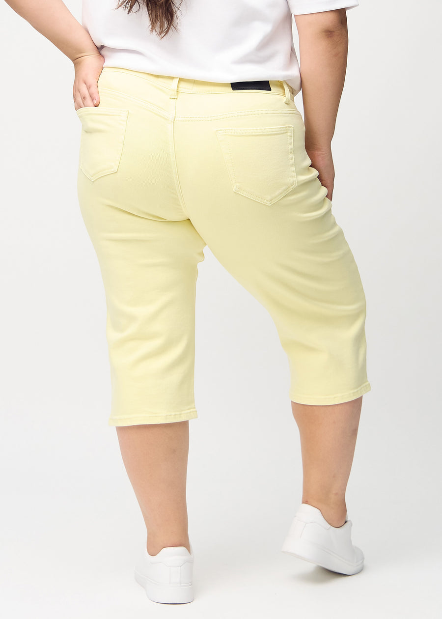 Hellgelbe regular Capris von hinten an einem Plus-Size-Model gesehen, sodass man das gesamte Produkt sehen kann.