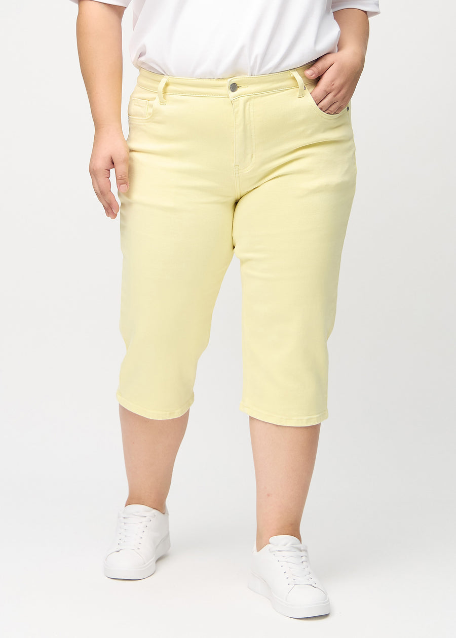Hellgelbe regular Capris, Modellname Lemonades, die an einem Plus-Size-Model gerade am Bein entlang verlaufen, von vorne gesehen.