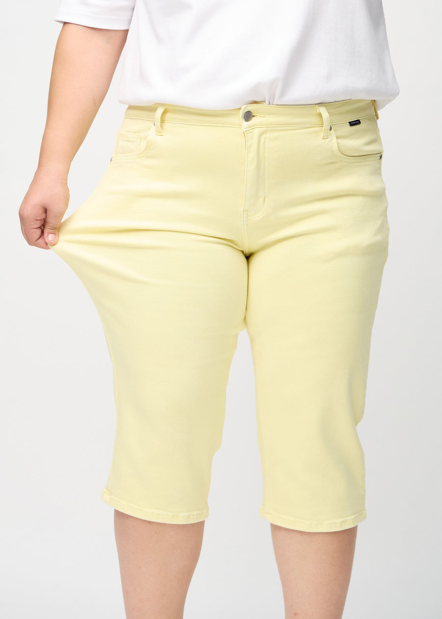 Das Plus-Size-Model zieht die Capris am Oberschenkel, um den Stretch zu zeigen.