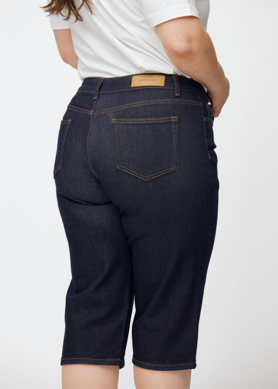 Tief dunkelblaue Denim-Capris für Damen in der Farbe Midnights von hinten nah auf einem Plus-Size-Model aufgenommen.