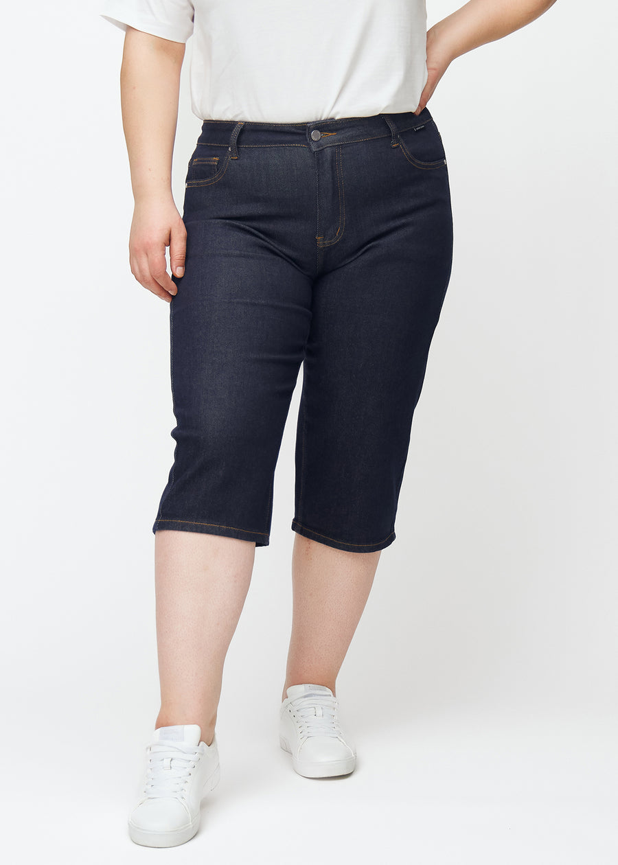 Tief dunkelblaue Denim-Capris für Damen in der Farbe Midnights mit Regular-Passform, von vorne auf einem Plus-Size-Model gesehen.