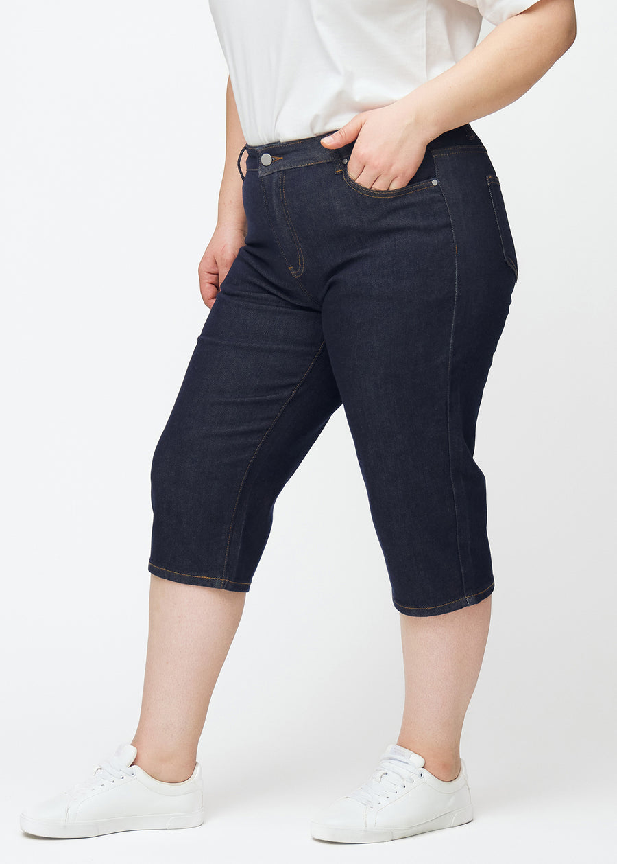 Tief dunkelblaue Denim-Capris für Damen in der Farbe Midnights mit Regular-Passform, von der Seite auf einem Plus-Size-Model gesehen.