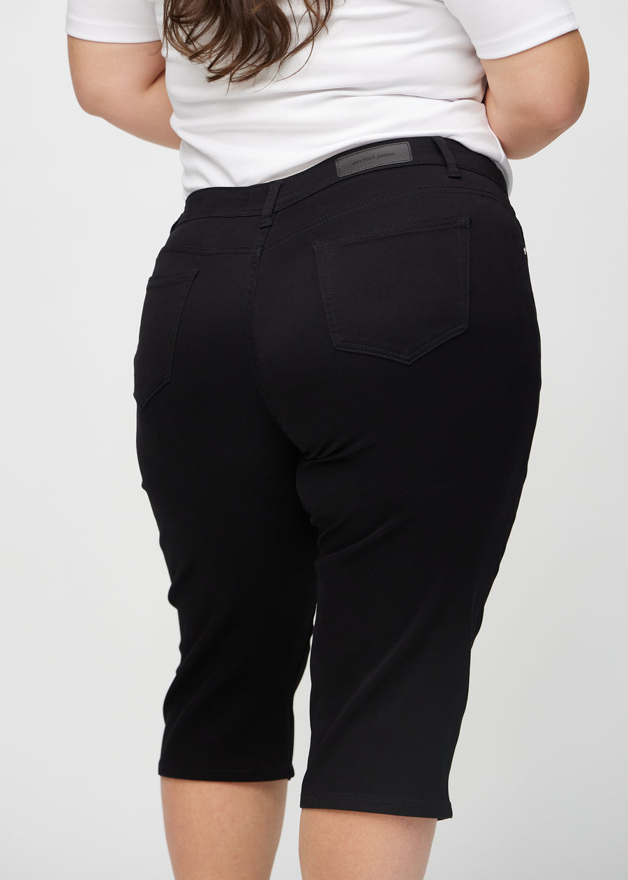 Schwarze regular Capris von hinten aus der Nähe an einem Plus-Size-Model gesehen, um Details zu zeigen.