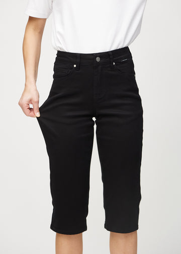 Das Model zieht die Capris am Oberschenkel, um den Stretch zu zeigen.