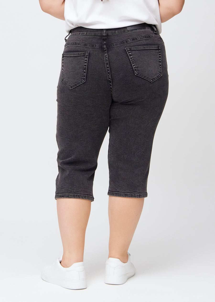 Dunkelgraue Denim-regular-Capris von hinten an einem Plus-Size-Model gesehen, damit man das gesamte Produkt sehen kann.