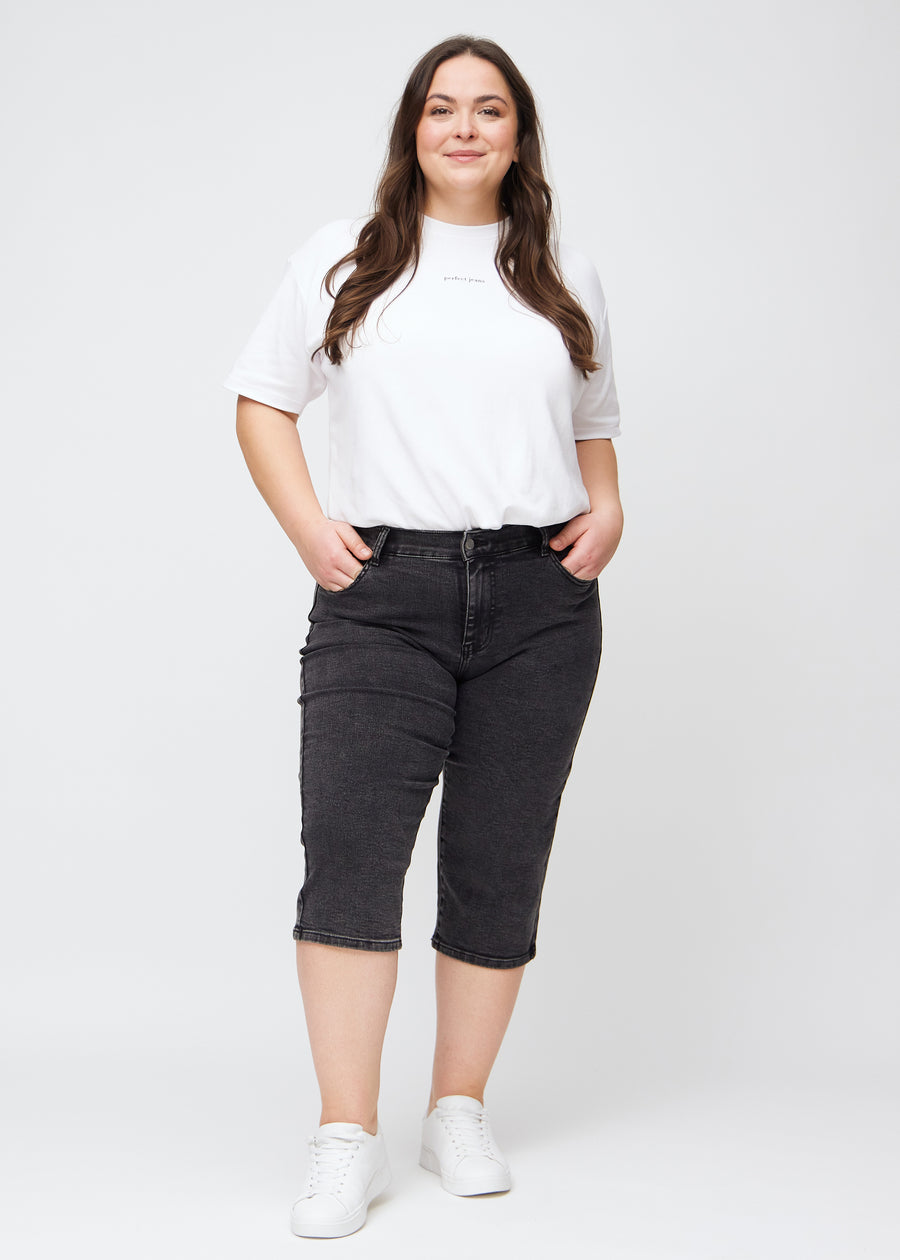 Ganzkörperbild eines Plus-Size-Models in dunkelgrauen Denim-regular-Capris.