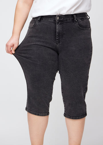 Das Plus-Size-Model zieht die Capris am Oberschenkel auseinander, um den Stretch zu zeigen.