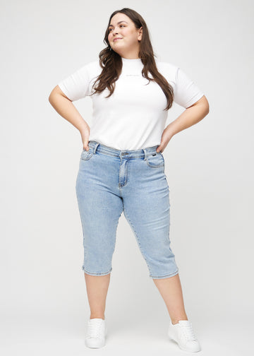 Ganzkörperbild eines Plus-Size-Models in hellblauen Denim-regular-Capris.